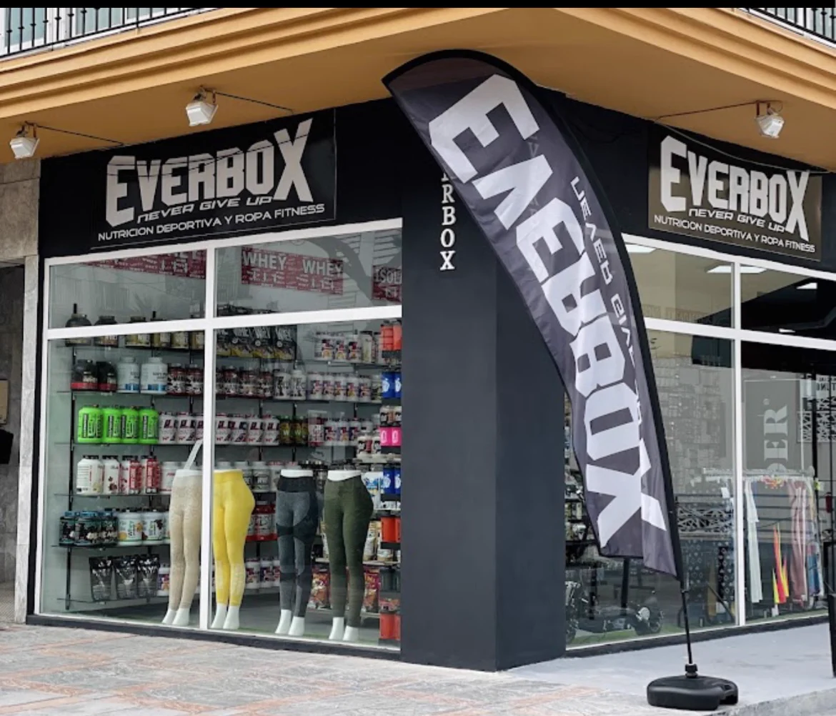 Fachada de Everbox en Fuengirola: rótulo negro con el lema Never give up, escaparate con botes de suplementos y mallas de ropa fitness